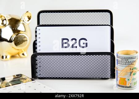 B2G - abbreviazione di business to government. B2G scritto in un quaderno su un supporto su sfondo bianco Foto Stock