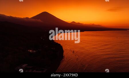 Vista panoramica con droni della costa con vulcano e tramonto con tranquillo oceano a Bali. Foto Stock
