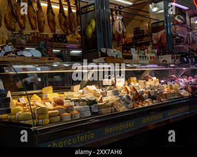 Santiago de Compostela, Spagna - 16 giugno 2024: Una vasta gamma di formaggi e salumi viene presentata in una bancarella del mercato, mettendo in evidenza le specialità locali e. Foto Stock