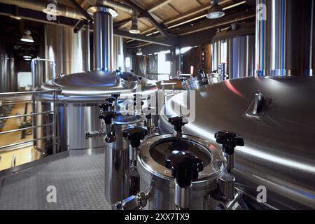 Le superfici brillanti dei serbatoi e delle valvole del birrificio dimostrano gli elevati standard di pulizia e precisione nel processo di estrazione. Foto Stock