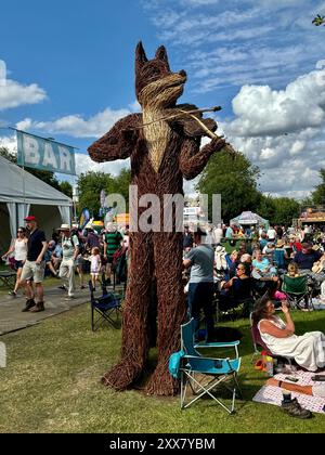 Persone sedute intorno al famoso violino di vimini che suona volpe al Cambridge Folk Festival 2024. Foto Stock