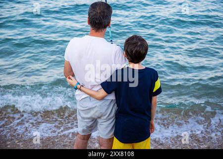 Padre e figlio, pesca al tramonto, vista sul retro in primo piano Foto Stock