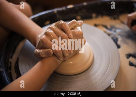 Hands Girl sulla ruota di potter prepara piatti di argilla. Processo di produzione Foto Stock