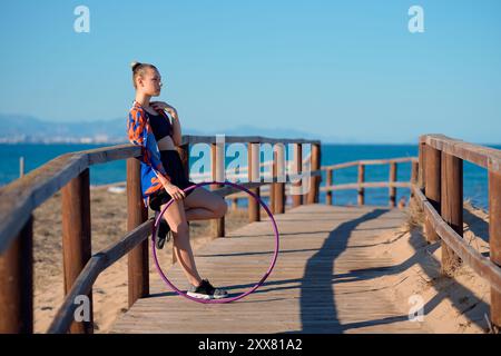 Un artista mostra le abilità di hula hoop lungo una passerella costiera Foto Stock