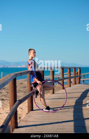 Un artista mostra le abilità di hula hoop lungo una passerella costiera Foto Stock