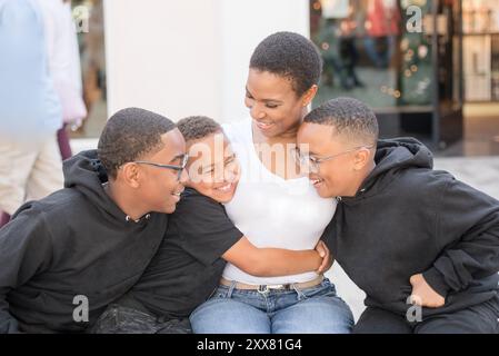 Figli che abbracciano madre stretta in centro Foto Stock