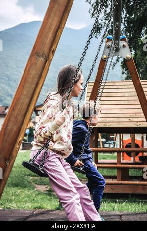 Due bambini carini che oscillano su un'altalena Foto Stock