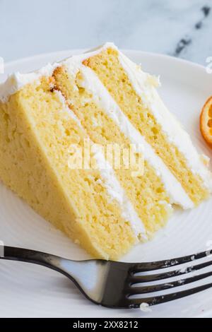 Fetta di torta a strati aromatizzata all'arancia con glassa bianca su un piatto Foto Stock