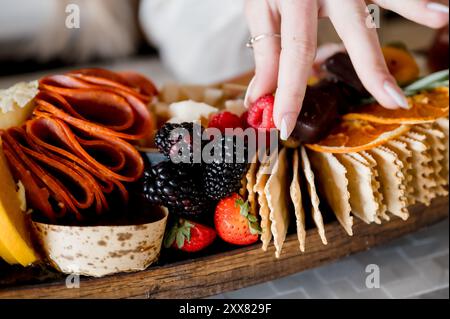 Mano di una donna che raccoglie un lampone dal pascolino di salumi Foto Stock