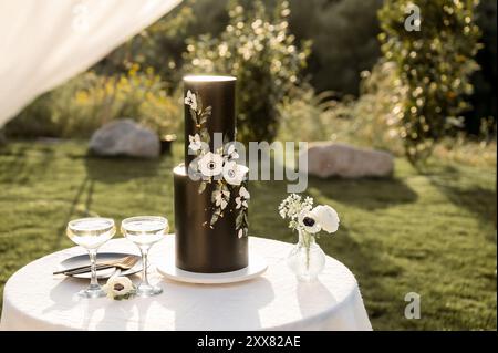torta nuziale nera con fiori bianchi su un piccolo tavolo rotondo Foto Stock
