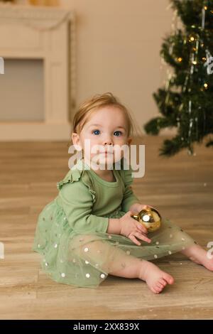 Bambina in abito verde con ornamento d'oro Foto Stock