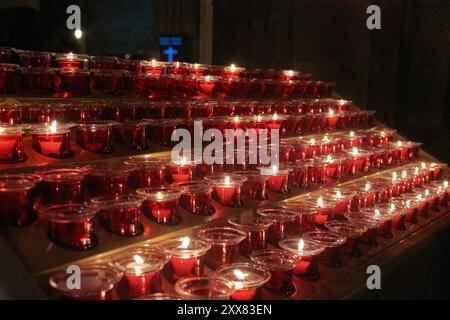 serie di candele accese su un altare che richiedono preghiere Foto Stock