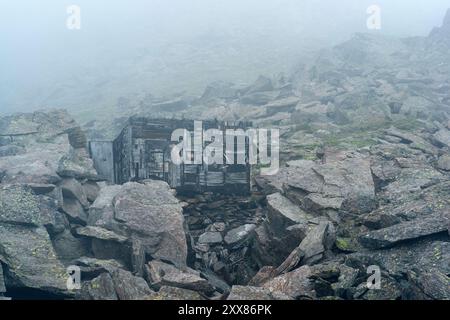rovine di un rifugio di montagna tra le rocce degli altopiani in una fitta nebbia Foto Stock