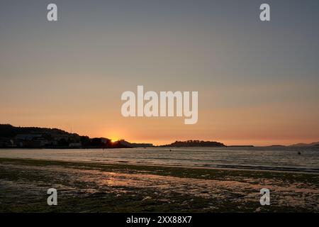 Straordinario tramonto a Ladeira Beach a Bayona, dove le vivaci tonalità arancioni dipingono il cielo, creando una scena affascinante e indimenticabile. Il sole cala Foto Stock