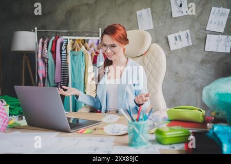 Foto di una ragazza assistente del negozio seduta in ufficio utilizzando il netbook per parlare con il cliente Foto Stock