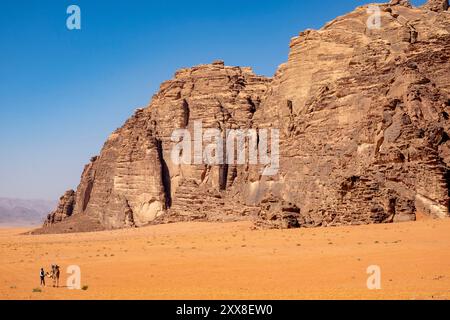 Giordania, deserto di Wadi Rum, patrimonio dell'umanità dell'UNESCO, beduini e il suo cammello di fronte alle scogliere di arenaria Foto Stock