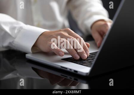 L'uomo d'affari è concentrato sul suo portatile e lavora diligentemente alla sua scrivania. La scena cattura il suo coinvolgimento con le attività digitali, mettendo in evidenza i suoi commi Foto Stock