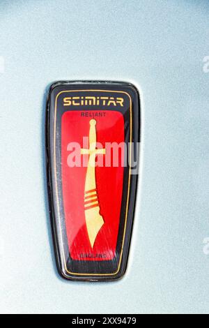 Primo piano dello stemma Reliant Scimitar con una spada a scimmia rossa su uno sfondo rosso e nero a scudo su sfondo blu. Foto Stock
