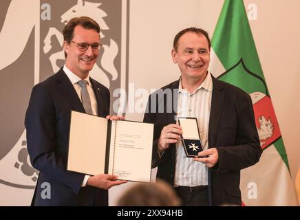 Duesseldorf, Germania. 23 agosto 2024. Il ministro Hendrik Wüst (l, CDU) presenta l'ordine al merito di Stato all'artista Jacques Tilly. Il noto costruttore di carri di carnevale di Düsseldorf Jacques Tilly è uno degli undici nuovi beneficiari dell'ordine al merito dello Stato della Renania settentrionale-Vestfalia. Crediti: Oliver Berg/dpa/Alamy Live News Foto Stock