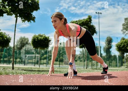 Una giovane donna con vitiligine si prepara a correre su una pista rossa in un parco, con un'espressione determinata sul viso. Foto Stock