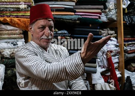 Il commerciante tessile di Gerusalemme Bilal Abu Khalaf si trova nel suo negozio nel quartiere cristiano della città Vecchia, circondato da tessuti che mostrano quello della sua famiglia Foto Stock