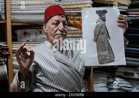 Il commerciante tessile di Gerusalemme Bilal Abu Khalaf si trova nel suo negozio nel quartiere cristiano della città Vecchia, circondato da tessuti che mostrano quello della sua famiglia Foto Stock