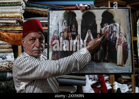 Il commerciante tessile di Gerusalemme Bilal Abu Khalaf si trova nel suo negozio nel quartiere cristiano della città Vecchia, circondato da tessuti che mostrano quello della sua famiglia Foto Stock