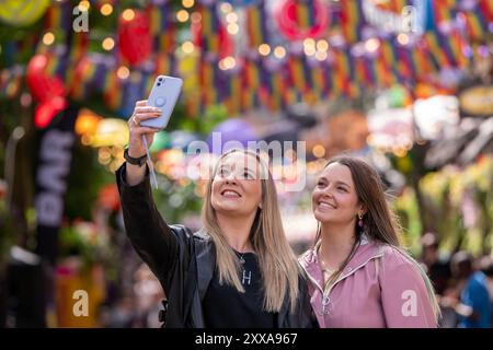 (l-r) i Mancuniani Devon e Lucy posano per un selfie su Canal Street nel quartiere Manchesters Gay mentre la tempesta Lilian non riesce a ostacolare l'inizio dell'orgoglio di Manchester per i primi arrivi. Manchester Pride 2024 . Il tema di quest'anno è "Buzzin to be Queer - A Hive of Progress” e gli organizzatori dicono che sperano che "unirà il popolo di Manchester” sotto il simbolo del Manchester Bee. Esibizioni di punta di Jessie J, Loreen, Sugababes, Rita ora e la più grande star di Showman Keala Settle. La prima parata del Pride di Manchester si è tenuta il 20 febbraio 1988, quando un'enorme protesta anti-sezione 28 si è tenuta presso l'ic Foto Stock