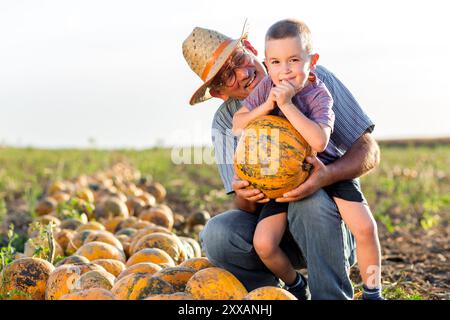 Agricoltore anziano con suo nipote nel campo delle zucche. Foto Stock