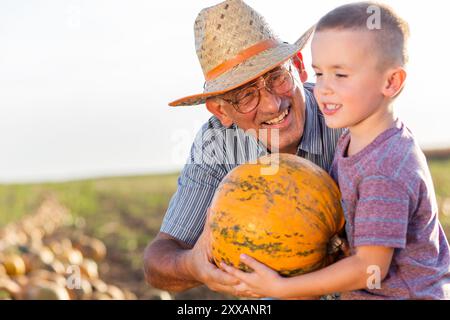 Agricoltore anziano con suo nipote nel campo delle zucche. Foto Stock