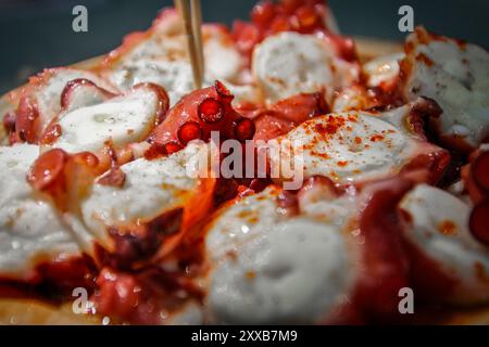 Galizia, Spagna. Polpo cotto preparato in tipico stile galiziano e servito in tipico stile galiziano su una tavola di legno. Foto Stock