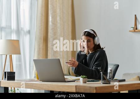 Una giovane donna lavora sul suo laptop a una scrivania nel suo ufficio domestico. Foto Stock