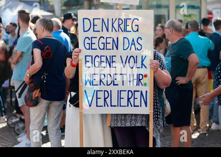 Heilbad Heiligenstadt, Germania. 23 agosto 2024. Le donne hanno un poster con lo slogan "perderai la guerra contro il tuo popolo" durante un evento della campagna elettorale AfD sulla piazza del mercato. Crediti: Matthias Bein/dpa/Alamy Live News Foto Stock