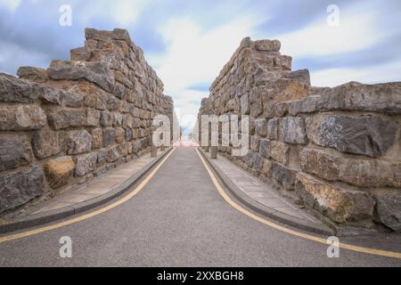 Una vista di un sentiero in pietra che conduce attraverso alte pareti di blocchi di pietra a Coldstones Cut, Pateley Bridge, North Yorkshire, Regno Unito. Foto Stock