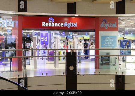 Howrah, Bengala Occidentale, India - 21 aprile 2024: Vista frontale esterna di uno showroom digitale di fiducia di notte, persone che fanno shopping all'interno Foto Stock