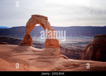 Ero sotto delicate Arch nel Parco Nazionale degli Arches. Un sole pomeridiano si attenuava in lontananza. Era un sentiero molto popolare nel parco. Foto Stock