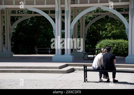 Vista posteriore delle coppie sedute sul panca del parco nel parco pubblico Foto Stock