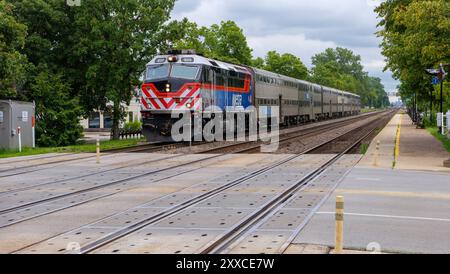 Treno pendolare BNSF Metra, guidato da una locomotiva F40PHM-3, che arriva alla stazione di Riverside, Illinois. Foto Stock