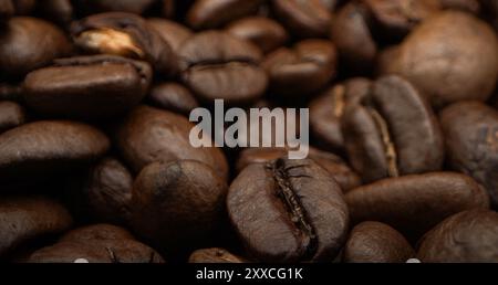 Un mucchio di chicchi di caffè impilati insieme, pronti per essere erogati in una deliziosa tazza di caffè. Primo piano di chicchi di caffè arabica tostati . Tipi diversi Foto Stock