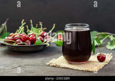 Bicchiere di succo di ciliegia acida con ciliegie rosse fresche, succo estivo Foto Stock