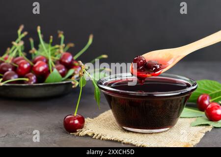 Marmellata di ciliegie acide nel vaso di vetro o nel recipiente con ciliegie acide crude fresche Foto Stock