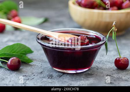 Marmellata di ciliegie acide nel vaso di vetro o nel recipiente con ciliegie acide crude fresche Foto Stock