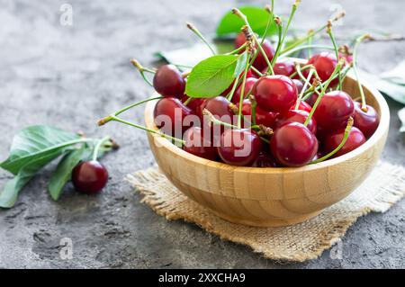 Ciliegie acide mature fresche in una ciotola su tavola rustica, frutti rossi estivi Foto Stock