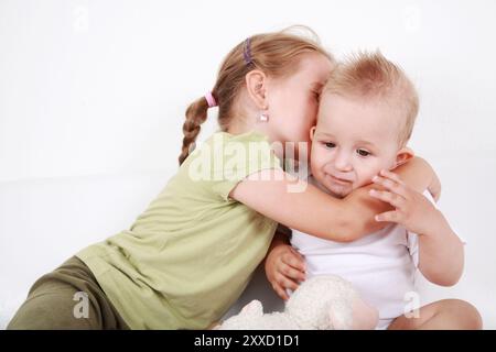 La sorella maggiore carina dà un bacio a suo fratello Foto Stock