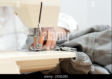 Mano femminile su una macchina da cucire elettrica Foto Stock