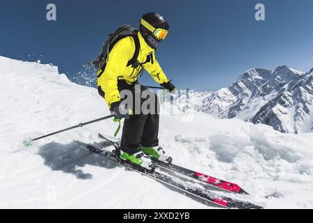 Sciatore professionista alla velocità prima di saltare dal ghiacciaio in inverno contro il cielo blu e le montagne Foto Stock