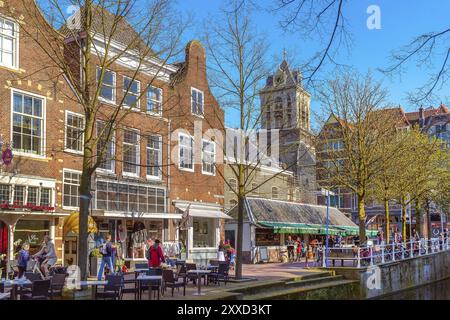 Delft, Paesi Bassi, 8 aprile 2016: Colorata vista sulla strada con tradizionali case olandesi, gente e canale Foto Stock