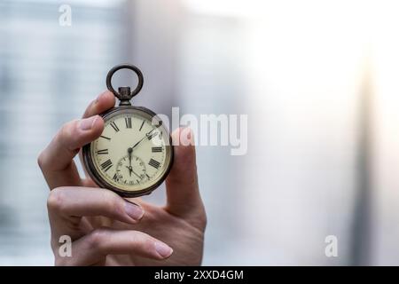 Il tempo passa vicino: L'uomo sta tenendo un orologio d'annata nella sua mano, contesto di affari, spazio di copia Foto Stock