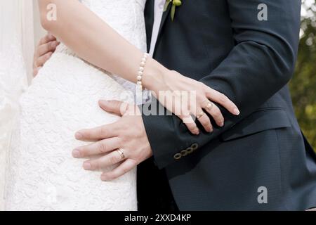 Primo piano di mani in abbracci di sposi novelli il giorno del matrimonio. Il concetto di felicità e tenerezza del matrimonio Foto Stock