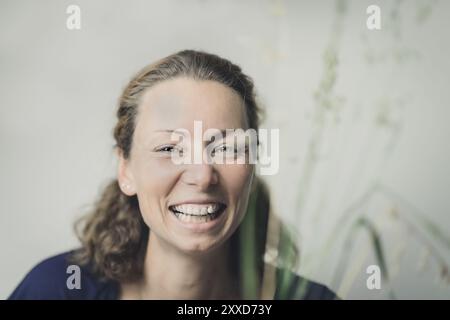 Una donna giovane e felice sorride allo spettatore Foto Stock